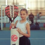 Een premium padelracket met ergonomisch ontwerp en geavanceerde materialen op een speelveld.