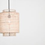 Een elegante rotan hanglamp die een warme, natuurlijke sfeer in een woonkamer creëert met subtiel licht en schaduwspel.
