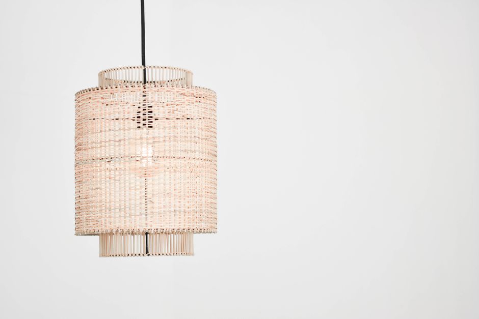 Een elegante rotan hanglamp die een warme, natuurlijke sfeer in een woonkamer creëert met subtiel licht en schaduwspel.